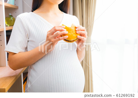 Pregnant woman eating hamburger Pregnant woman eating hamburger 61269192
