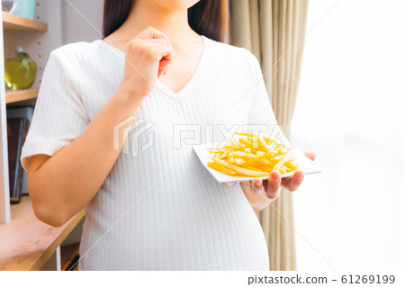 Pregnant woman eating french fries 61269199