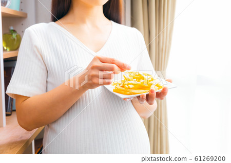 Pregnant woman eating french fries 61269200