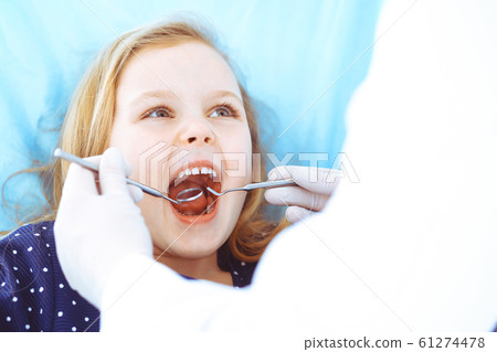 Little baby girl sitting at dental chair with open mouth during oral check up while doctor. Visiting dentist office. Medicine concept. Toned photo 61274478