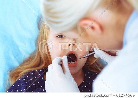 Little baby girl sitting at dental chair with open mouth during oral check up while doctor. Visiting dentist office. Medicine concept. Toned photo 61274569