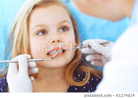 Little baby girl sitting at dental chair with open mouth during oral check up while doctor. Visiting dentist office. Medicine concept. Toned photo 61274824