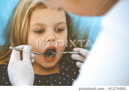 Little baby girl sitting at dental chair with open mouth during oral check up while doctor. Visiting dentist office. Medicine concept. Toned photo 61274880