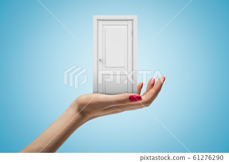 Female hand holding white doorway on blue background Female hand holding white doorway on blue background 61276290