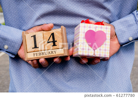 Businessman holding 14 February wooden calendar and heart gift box. Valentine day concept 61277780