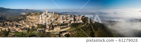 Big drone aerial landscape panorama of the wonderful village of San Gimignano a small walled medieval hill town in the province of Siena, Tuscany in morning mystic fog. Big drone aerial landscape panorama of the wonderful village of San Gimignano a small walled medieval hill town in the province of Siena, Tuscany in morning mystic fog. 61279028