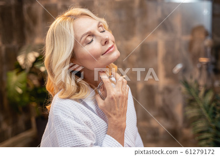 Beautiful lady spraying perfume on her neck 61279172