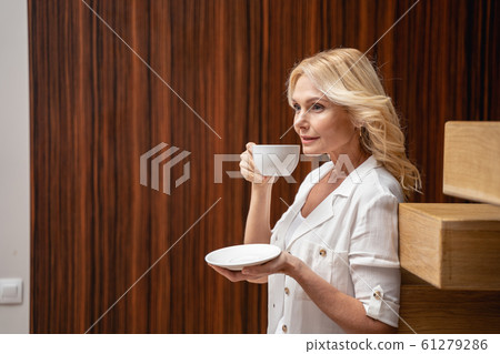 Beautiful modern serene woman drinking coffee indoors Beautiful modern serene woman drinking coffee indoors 61279286