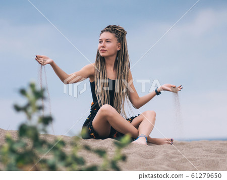 Young woman with dreadlocks pouring sand 61279650