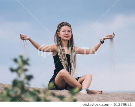 Young woman with dreadlocks pouring sand 61279651
