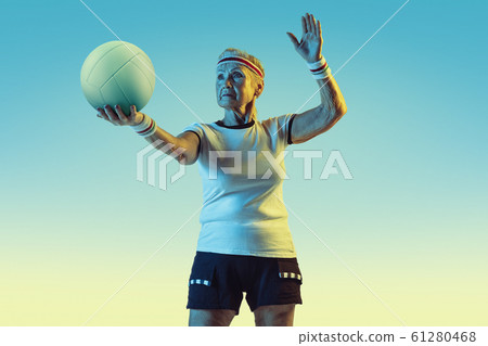 Senior woman training in volleyball in sportwear on gradient background in neon light Senior woman training in volleyball in sportwear on gradient background in neon light 61280468