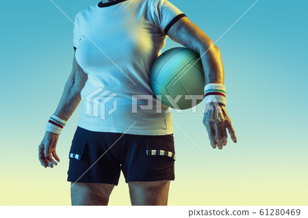 Senior woman training in volleyball in sportwear on gradient background in neon light Senior woman training in volleyball in sportwear on gradient background in neon light 61280469