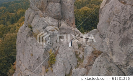 Newlyweds stand on a high slope of the mountain. Groom and bride. Aerial view 61281256