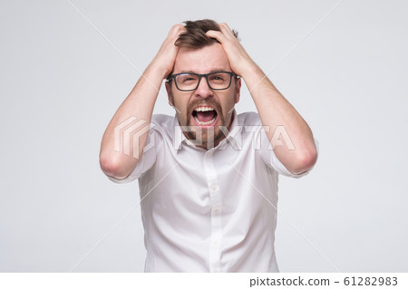 young man in glasses looking desperate and frustrated, stressed, unhappy and annoyed, shouting and screaming 61282983