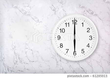White round wall clock on white natural marble background. Six o'clock. 61285013
