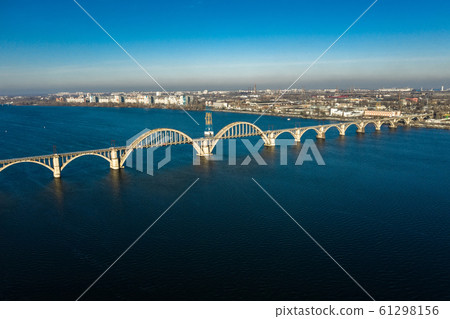 Aerial panoramic view on old arch railway Merefo-Kherson bridge across the Dnieper river in Dnepropetrovsk. View of the left bank of Dnipro city. 61298156