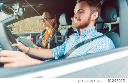 Driving instructor with student in car teaching how to drive 61298925