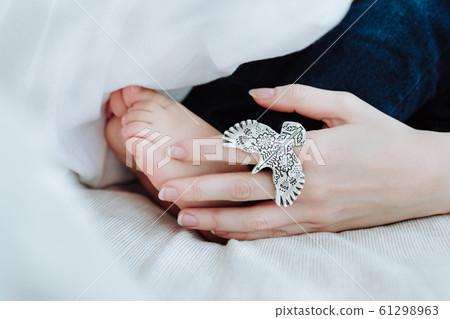 Maternal hand touches baby feet 61298963