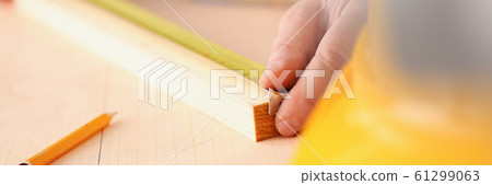 Arms of worker measuring wooden bar closeup 61299063