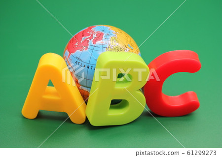 Colored ABC-letters of the English alphabet and small toy globe on a green background. Learning foreign language. English for beginners. Colored ABC-letters of the English alphabet and small toy globe on a green background. Learning foreign language. English for beginners. 61299273