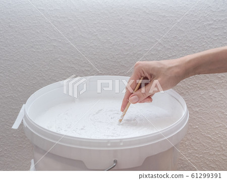 Worker mixes construction putty in a bucket. Worker mixes construction putty in a bucket. 61299391