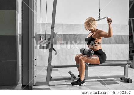 Female bodybuilder training back on simulator. 61300397