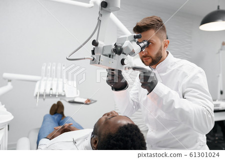 Male dentist examining teeth of male patient in clinic Male dentist examining teeth of male patient in clinic 61301024
