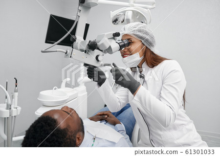 Positive female dentist curing teeth of male patient Positive female dentist curing teeth of male patient 61301033