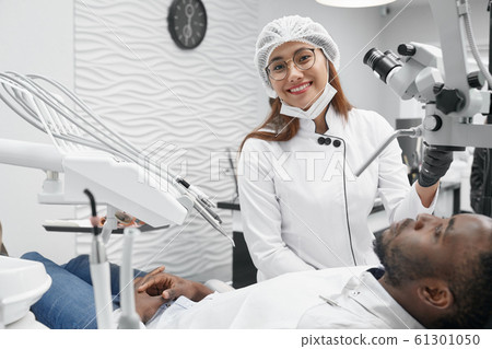 Female dentist posing while curing teeth in clinic 61301050