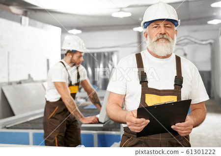 Male engineer in uniform and helmet keeping folder 61301222