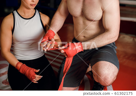 Cropped young caucasian muscular man help young woman to binds the bandage on her hand Cropped young caucasian muscular man help young woman to binds the bandage on her hand 61302175