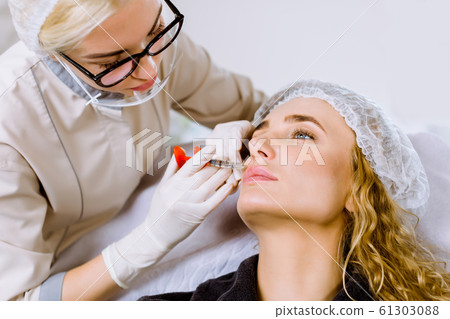 Pretty blond woman gets beauty facial injections. Anti-aging, nourishing, vitamins treatment at spa salon. Aesthetic cosmetology 61303088