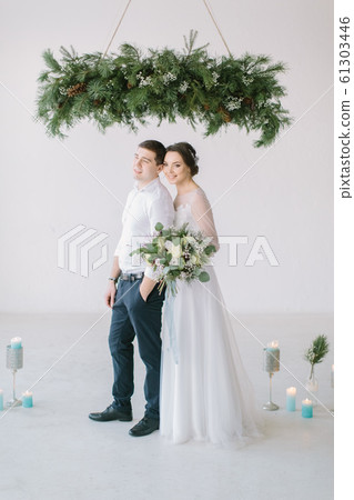 Very beautiful wedding of amazing couple. Wedding ceremony in light white room decorated with flowers and candles. 61303446