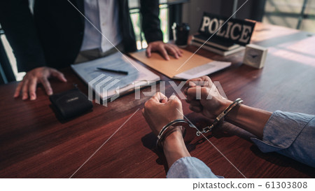 suspect with handcuffs being interviewed in suspect with handcuffs being interviewed in 61303808