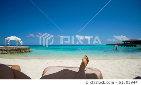 Feet tourist relax at Maldives turquoise sea white sand tropical beach paeadise destinaton 61303944