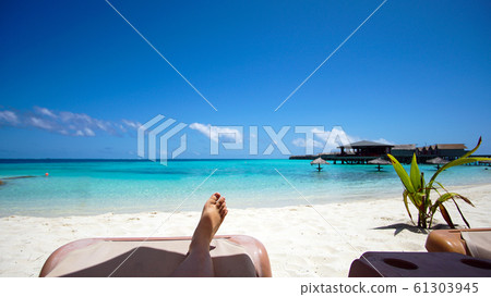 Feet tourist relax at Maldives turquoise sea white sand tropical beach paeadise destinaton Feet tourist relax at Maldives turquoise sea white sand tropical beach paeadise destinaton 61303945