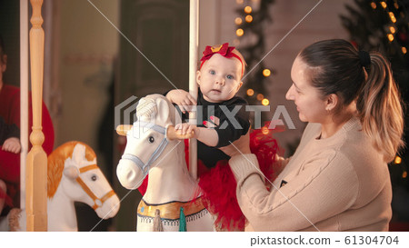 Christmas concept - smiling plump mother in beige sweater with her baby in christmas studio 61304704
