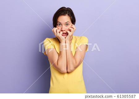 Frightened and surprised girl with her hands near her face and with open mouth. 61305587