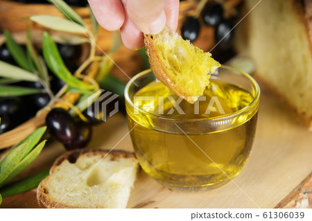 Close up of a glass bowl full of olive oil with bread and olive brunches. healthy fats Close up of a glass bowl full of olive oil with bread and olive brunches. healthy fats 61306039
