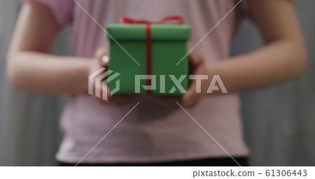 young woman stand and show green gift box with red ribbon bow 61306443