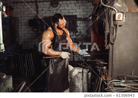 careful blacksmith holding metal in hands 61306943