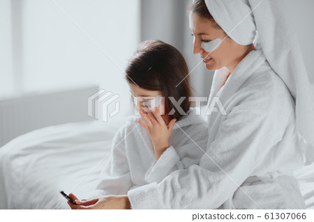 good-looking woman and hid daughter sit together on bed in beauty patches at home good-looking woman and hid daughter sit together on bed in beauty patches at home 61307066