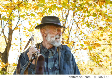 Thoughtful hunter stand with gun looking away Thoughtful hunter stand with gun looking away 61307158