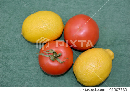 Yellow lemons and red tomatoes on green. 61307783