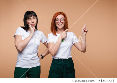Two female posing showing empty place and thinking 61308281