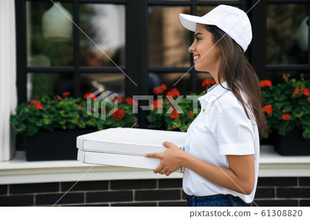 Smiling deliverywoman delivering boxes of pizza. Smiling deliverywoman delivering boxes of pizza. 61308820