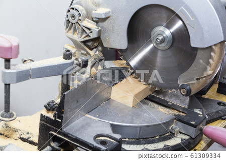 A miter saw making a compound cut through construction lumber. 61309334