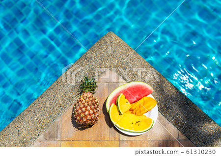 Juicy tropical fruits set at pool edge with Juicy tropical fruits set at pool edge with 61310230