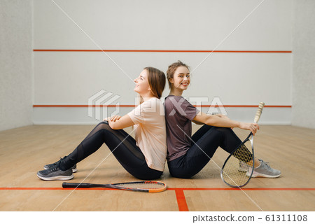Players with squash rackets sits back to back Players with squash rackets sits back to back 61311108