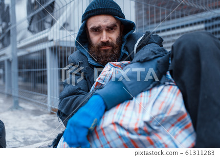 Male bearded beggar lies on city street Male bearded beggar lies on city street 61311283